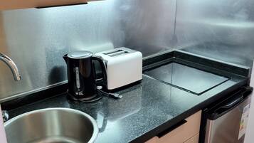 Une cuisine compacte équipée d’un four à micro-ondes, d’un grille-pain, d’une machine à café, d’un évier et d’un lave-vaisselle.