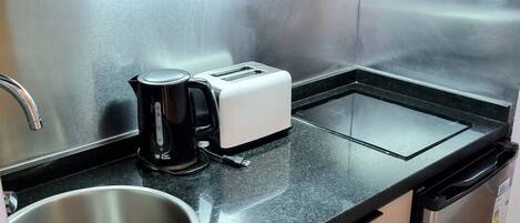 Cocina compacta equipada con microondas, tostadora, cafetera, lavaplatos y fregadero.