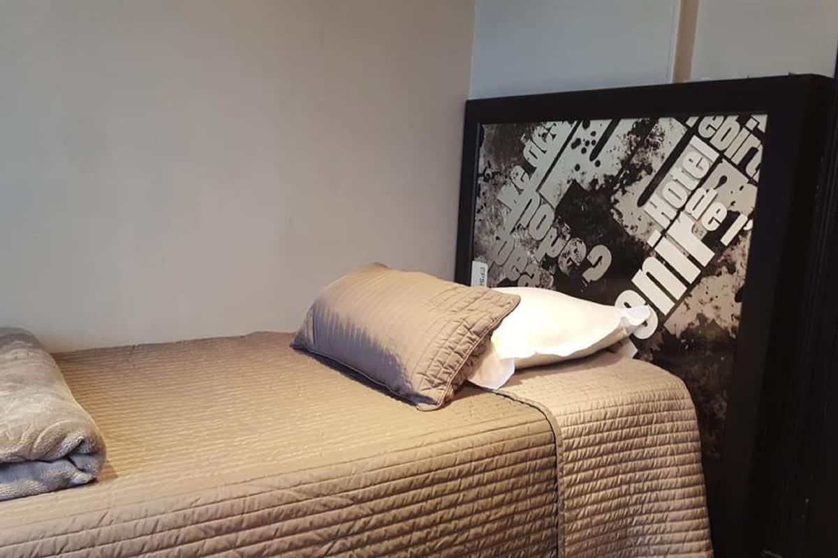 A neatly made bed with a beige quilt, a folded blanket, and two pillows.