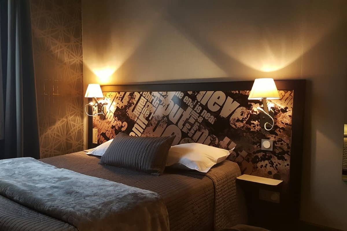 A hotel room with a large bed, two bedside lamps, and a wall with a textured design.