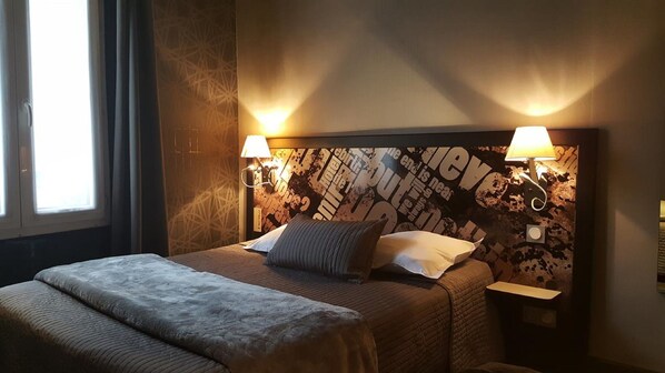 Una habitación de hotel con una cama grande, dos lámparas de noche y una pared con diseño texturizado.