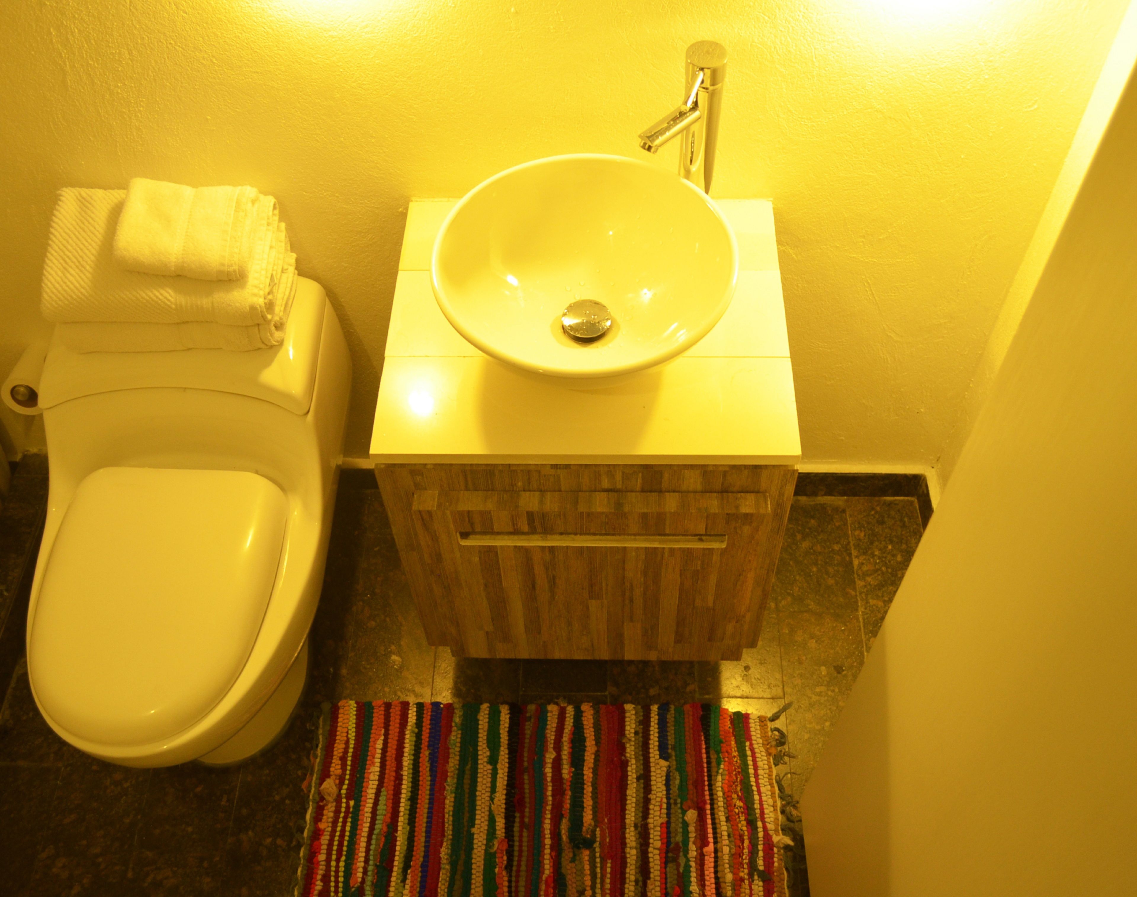 A bathroom with a toilet, a sink, and a wooden cabinet.