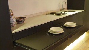 A modern kitchen with a dark countertop, a stainless steel sink, and a wooden floor. - Hotel Living 55 (Bogotá)