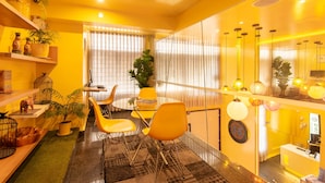 A modern hotel room with a yellow color scheme, a round dining table with yellow chairs, a large mirror, and a reception desk. - Hotel Living 55 (Bogotá)