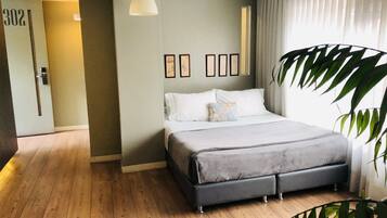 Un dormitorio con cama, una puerta con número, una lámpara colgante y una planta.