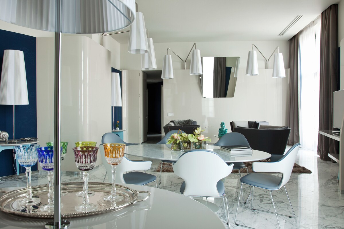 Un espace repas moderne avec une table ronde, des chaises blanches et un vase de fleurs.