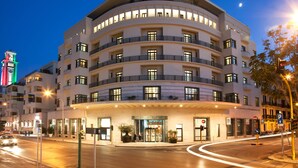 A multi-story hotel with a curved facade, multiple balconies, and a ground-level entrance with a glass door. - JR Hotels Bari Grande Albergo delle Nazioni (Bari)
