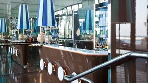 A modern bar area with reflective surfaces and blue-striped umbrellas. - JR Hotels Bari Grande Albergo delle Nazioni (Bari)