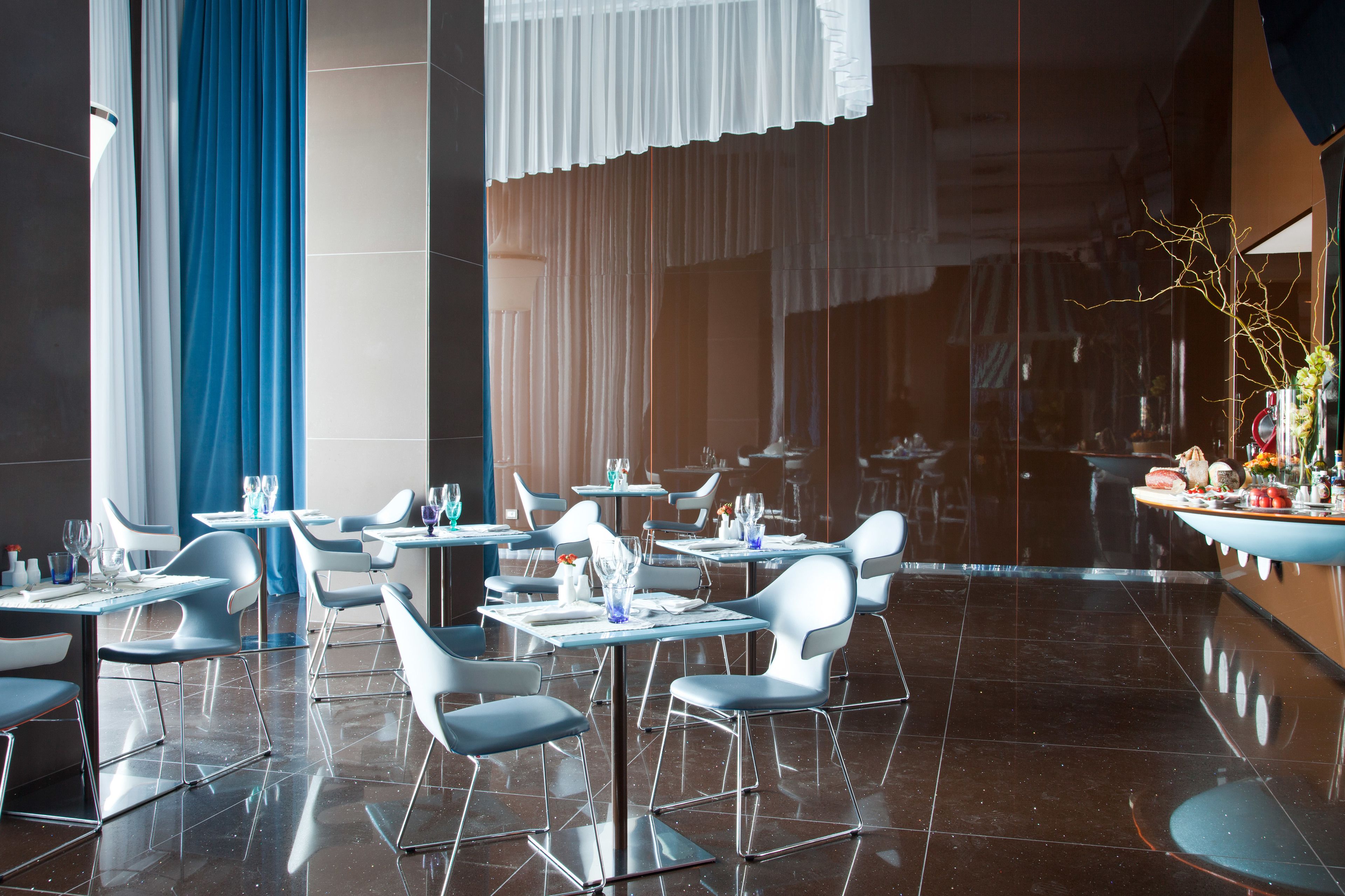Un restaurant moderne avec des chaises et des tables blanches, et un sol ciré.