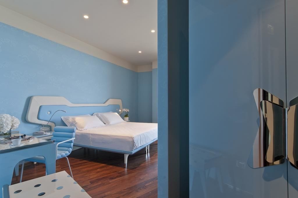 A bedroom with a bed, a desk, and a chair.