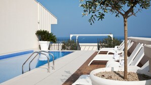 A rooftop pool with a clear view of the ocean, white lounge chairs, and a potted tree. - JR Hotels Bari Grande Albergo delle Nazioni (Bari)