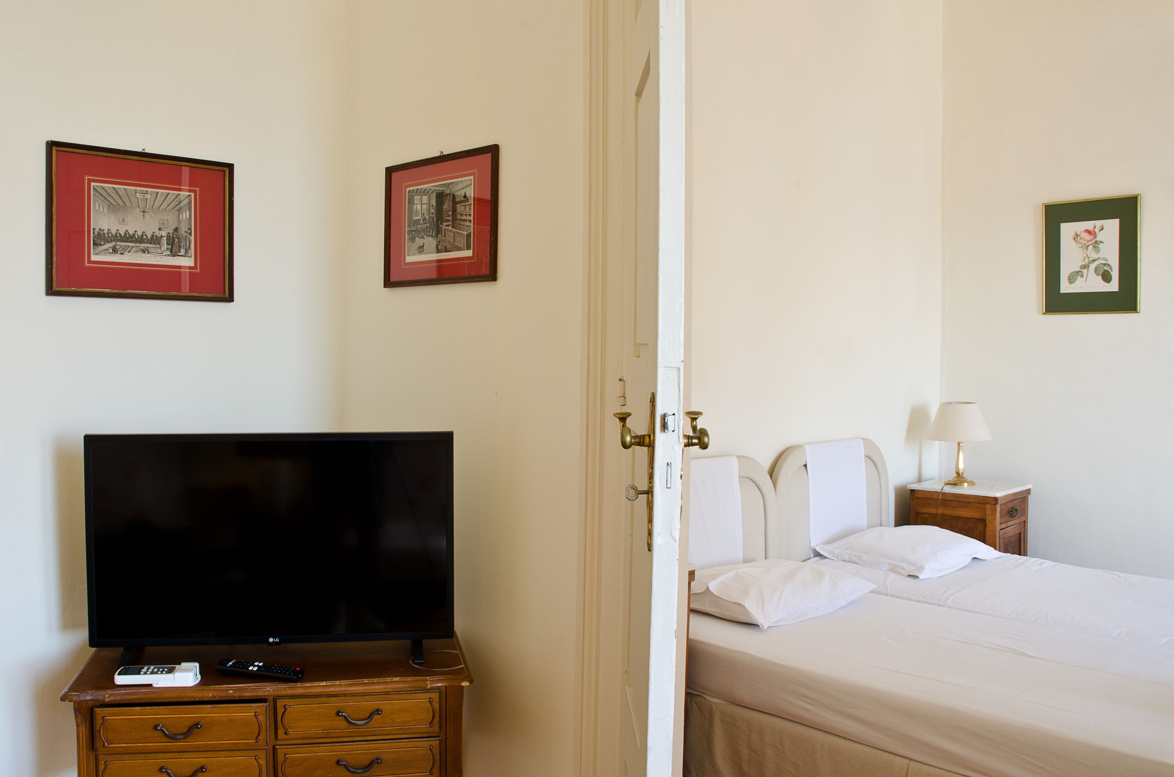 Ein Hotelzimmer mit einem Bett, einem Fernseher, einem Schminktisch und gerahmten Bildern an der Wand.
