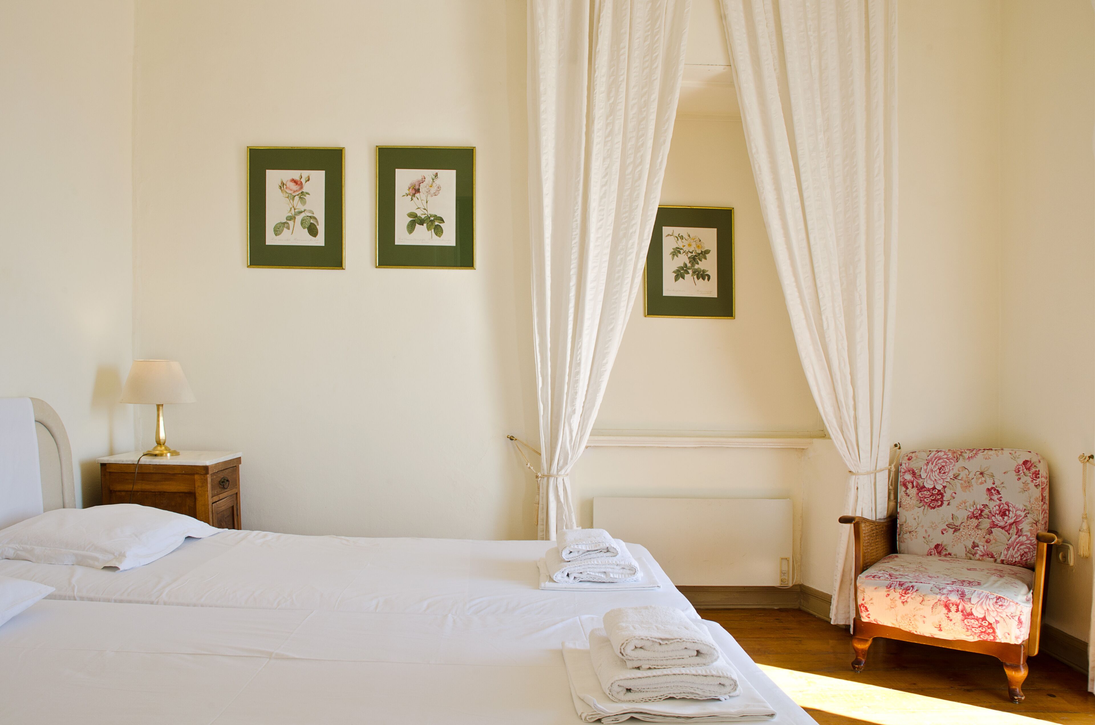 A bedroom with a bed, a chair, a nightstand, and a lamp.