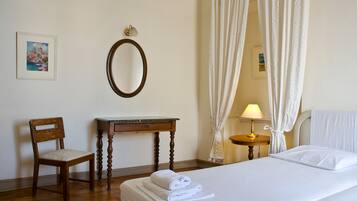 Une chambre d’hôtel avec un lit, une chaise, un bureau, une lampe et un miroir.