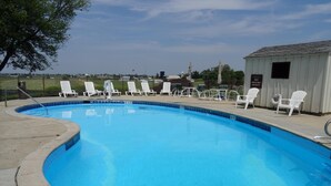 A swimming pool with white lounge chairs and a small shed.
