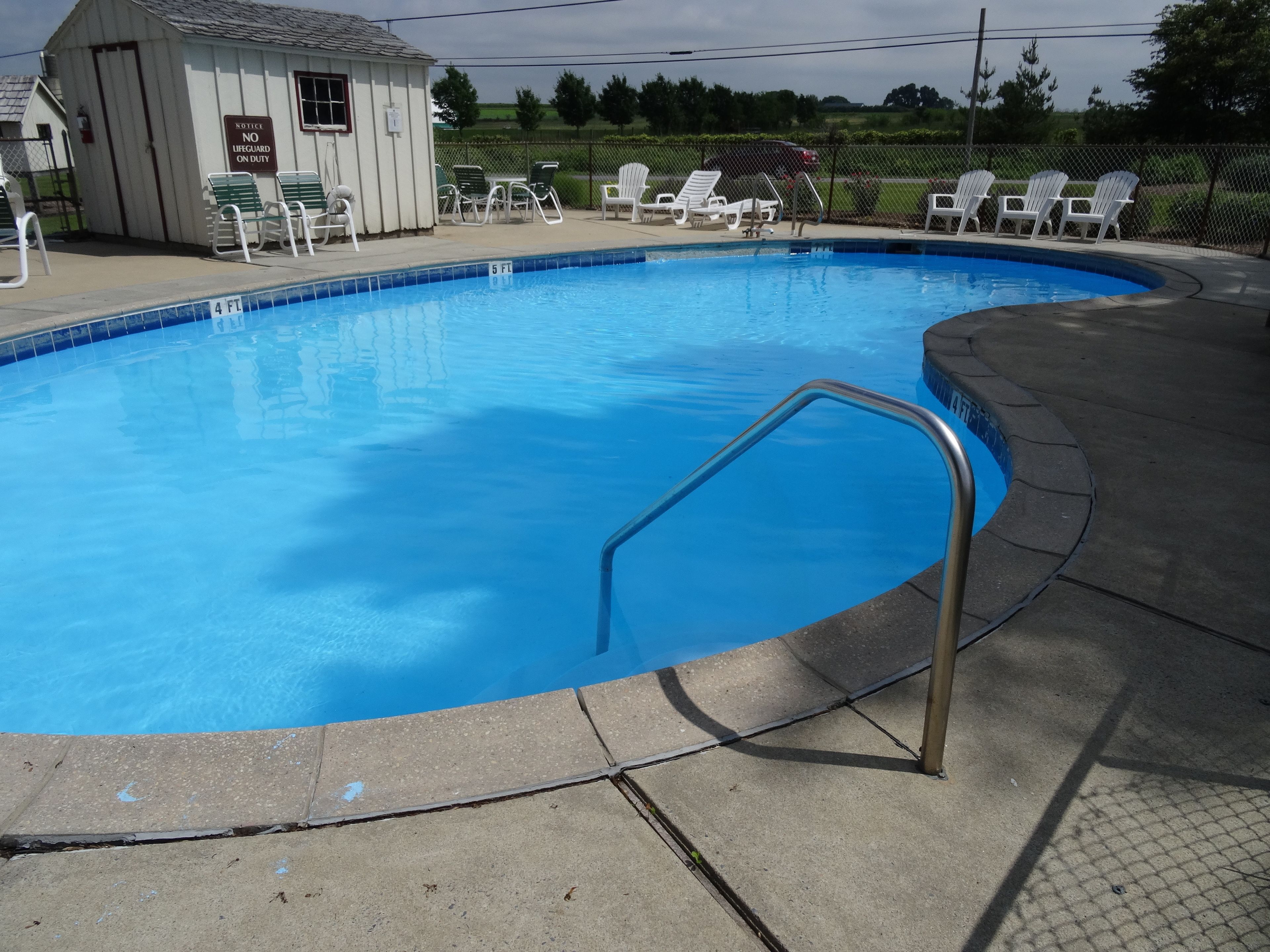 A swimming pool with a lifeguard station, lounge chairs, and a fenced area.
