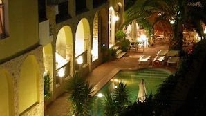 A pool area with lounge chairs, a small table, and a statue. - Hotel Pighi (Kassandra)