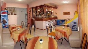 A bar area with a counter, chairs, and tables. - Hotel Pighi (Kassandra)