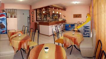 A bar area with a counter, chairs, and tables.