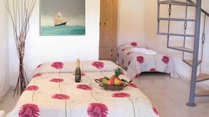A room with two beds, a painting of a sailboat, a bottle of champagne, and a fruit basket. - Hotel Pighi (Kassandra)