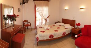 A well-lit bedroom with a bed, a chair, a desk, and a dresser. - Hotel Pighi (Kassandra)