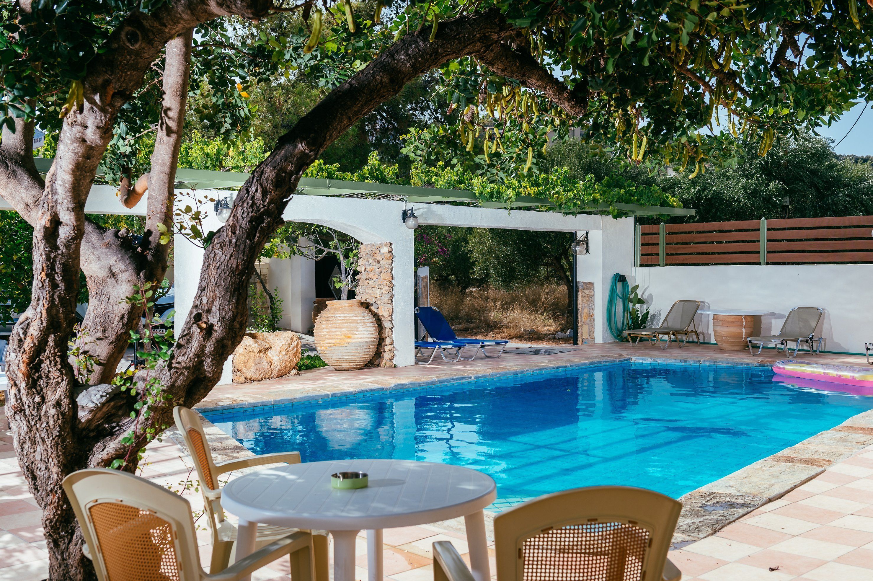 A pool area with lounge chairs, a table, and a pergola.