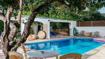 A pool area with lounge chairs, a table, and a pergola.