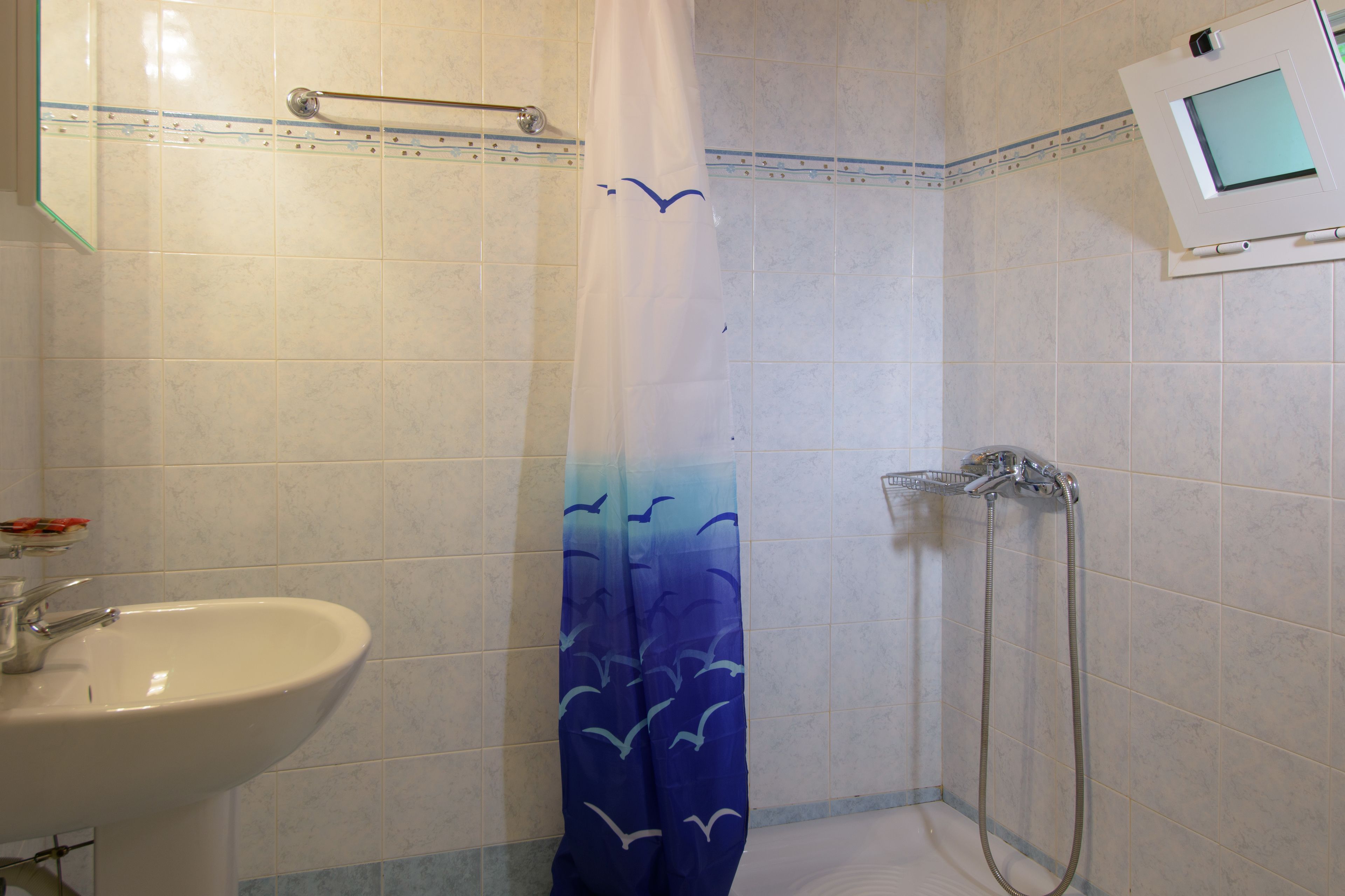 A bathroom with a shower, a sink, and a towel rack.