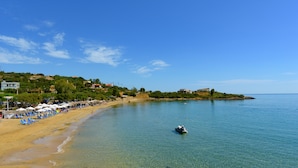 Ein Strand mit klarem Wasser, Liegestühlen und Sonnenschirmen.