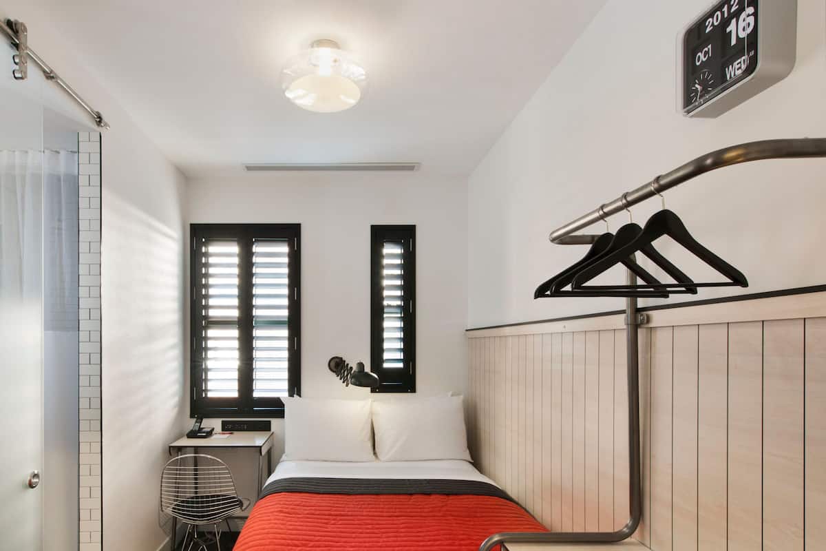 Une chambre d’hôtel moderne équipée d’un lit, d’un bureau, d’une chaise et d’une armoire.