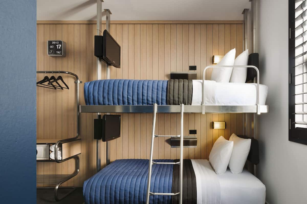 Une chambre avec un lit superposé, un mur en bois, un calendrier, une télévision et un petit bureau.