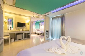 A hotel room with a large bed, a TV, a desk, and a bathroom. - The Verandah (Krabi)