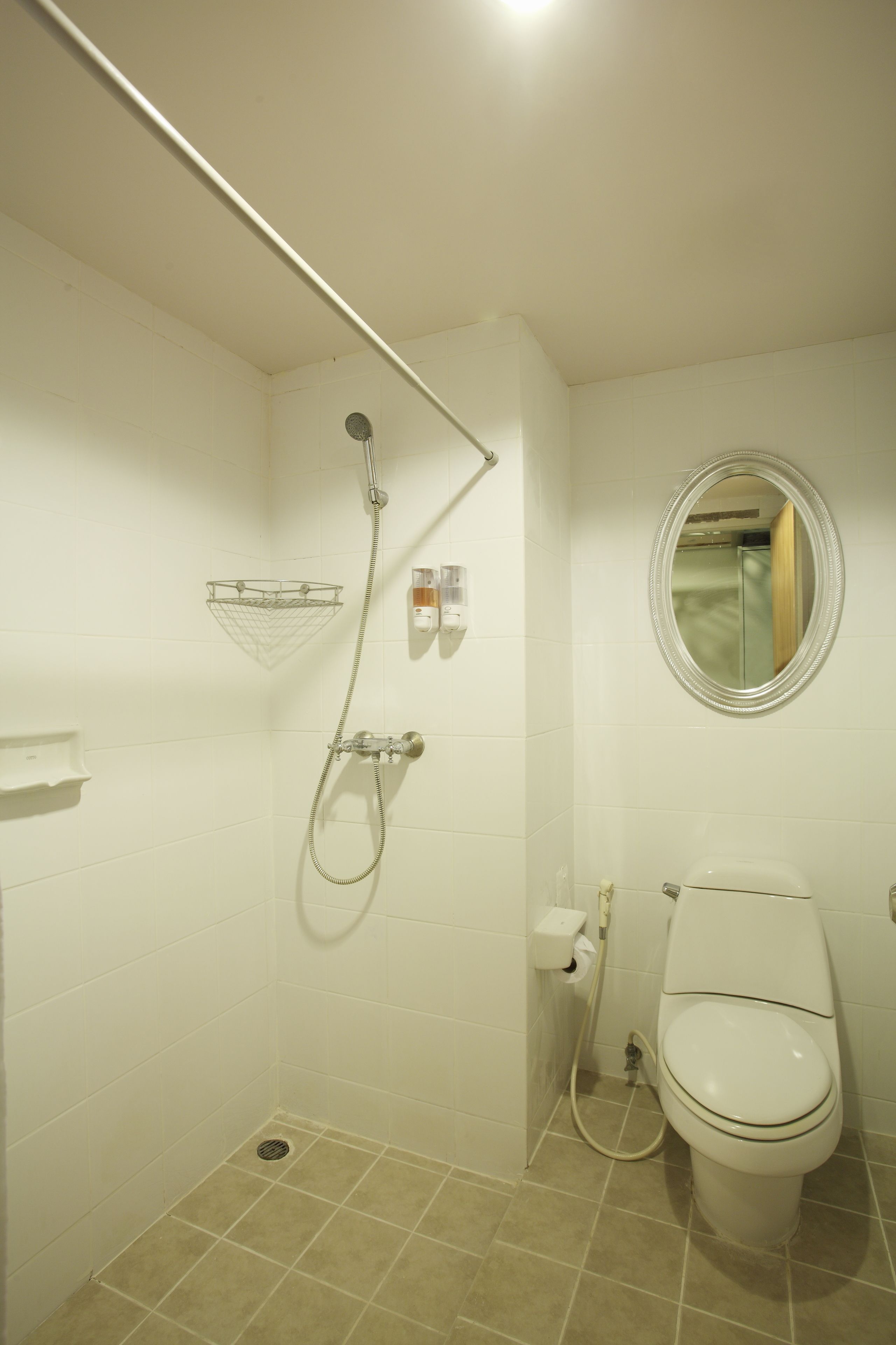 A small bathroom with a shower, toilet, and a mirror.