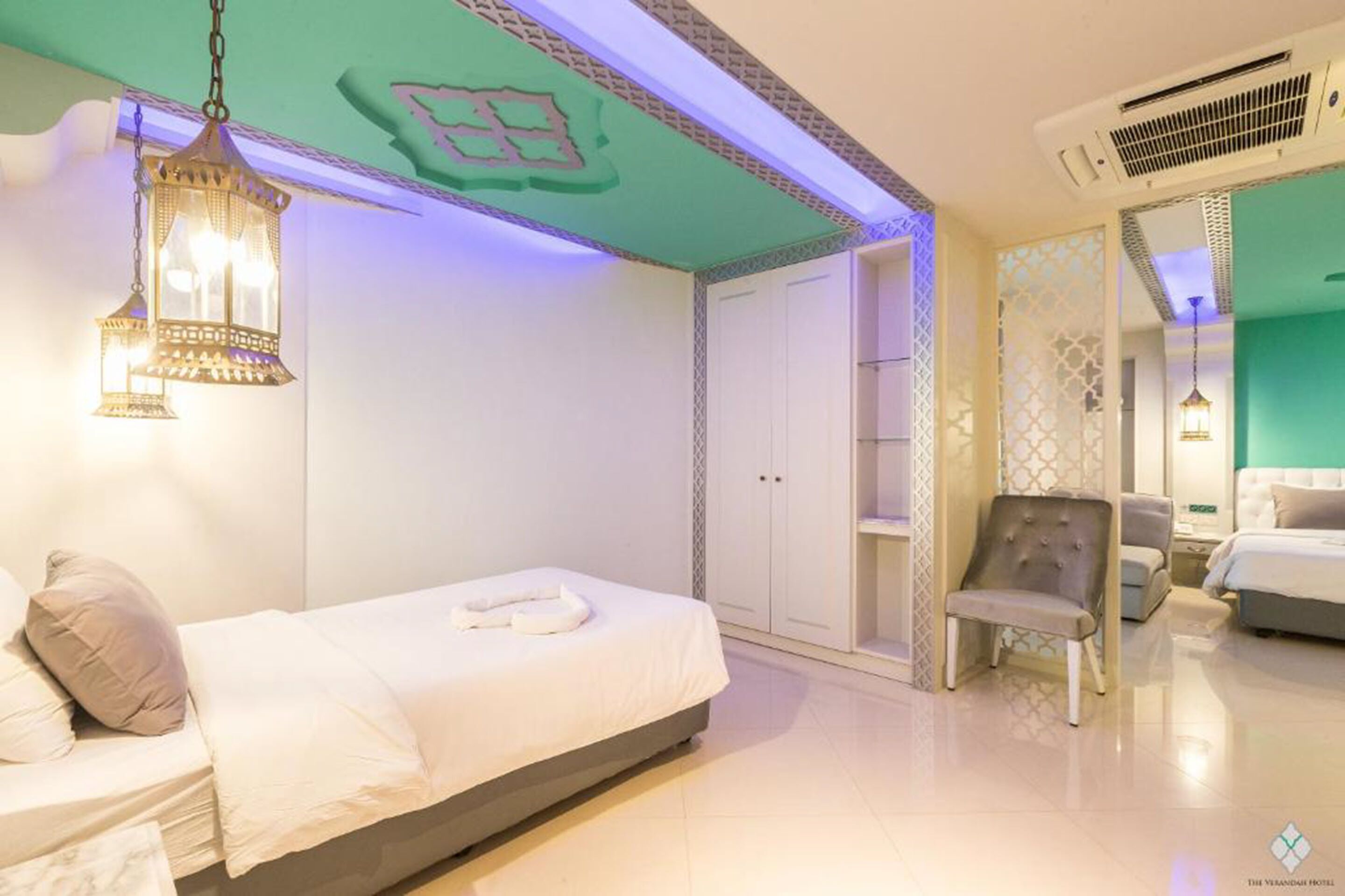 Une chambre d’hôtel moderne comprenant un lit, une chaise, une armoire et une lanterne décorative.