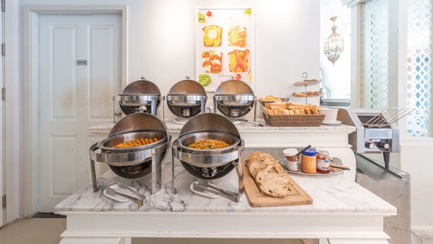 A buffet setup with multiple food bowls and a cutting board with bread and condiments.