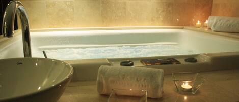 A bathroom with a bathtub, a sink, and a glass candle holder with a lit candle.
