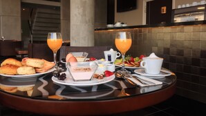 Ein Frühstückstisch mit Croissants, Obst, Joghurt und Orangensaft.