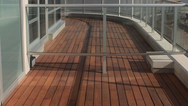 Ein Holzdeck mit Glasgeländern und Blick auf das Meer.