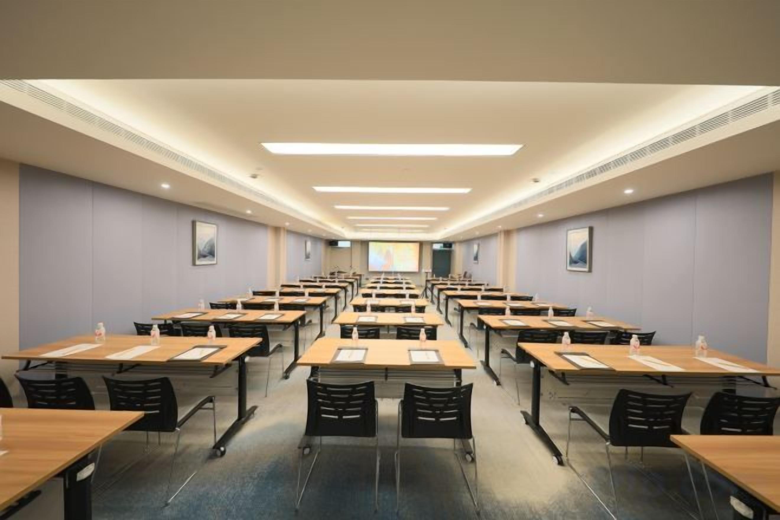 A conference room with rows of tables and chairs, equipped with water bottles and notepads.
