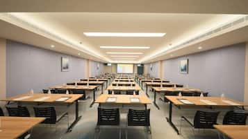A conference room with rows of tables and chairs, equipped with water bottles and notepads.