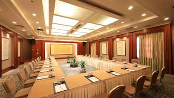 A conference room with a long table, chairs, and a projector screen.