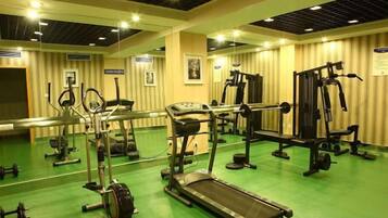 A gym with exercise equipment, a mirrored wall, and a green floor.