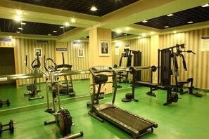 A gym with exercise equipment, a mirrored wall, and a green floor. - Yucheng Hotel (Suzhou)