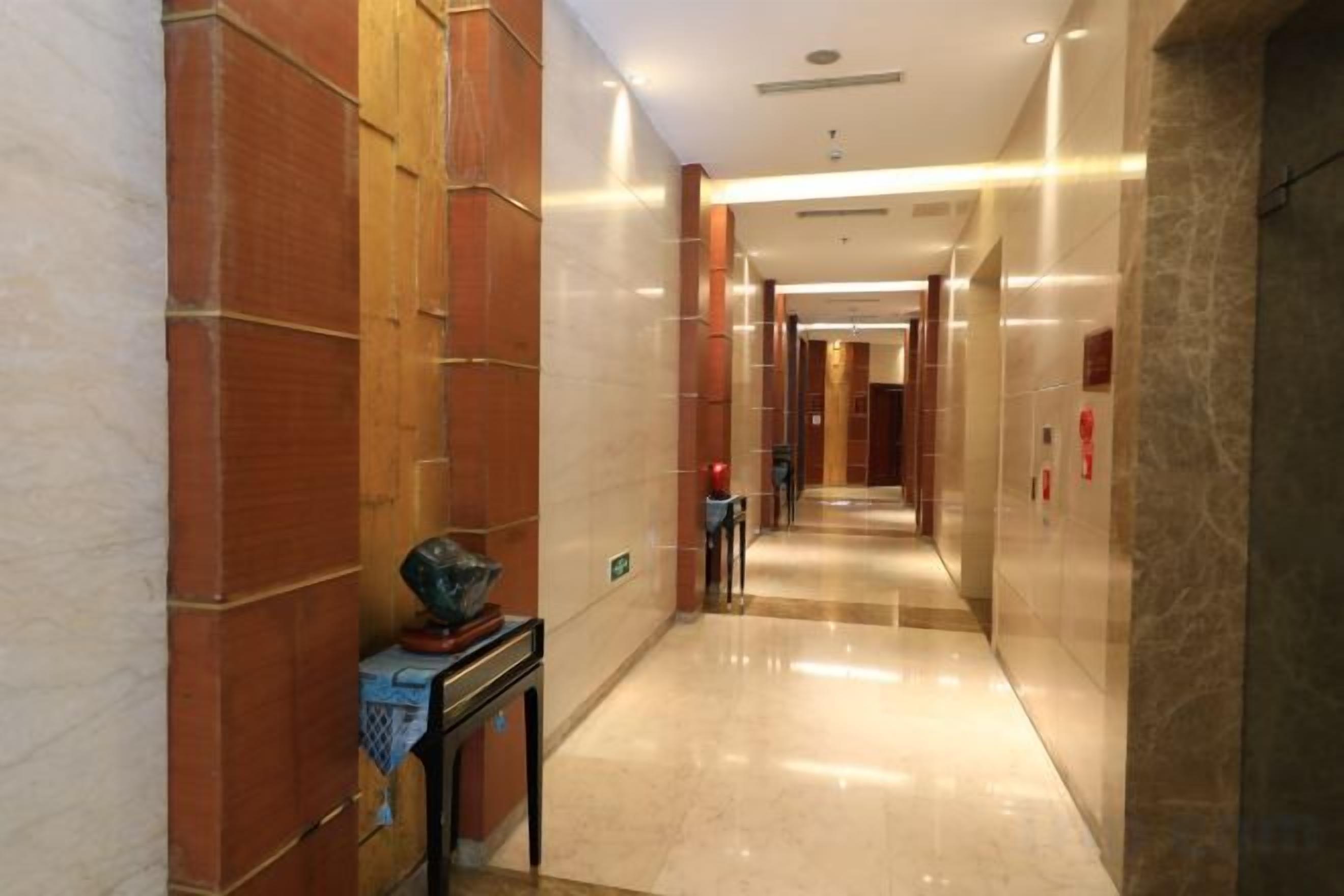 A corridor with marble walls and a polished floor, leading to a door at the end.