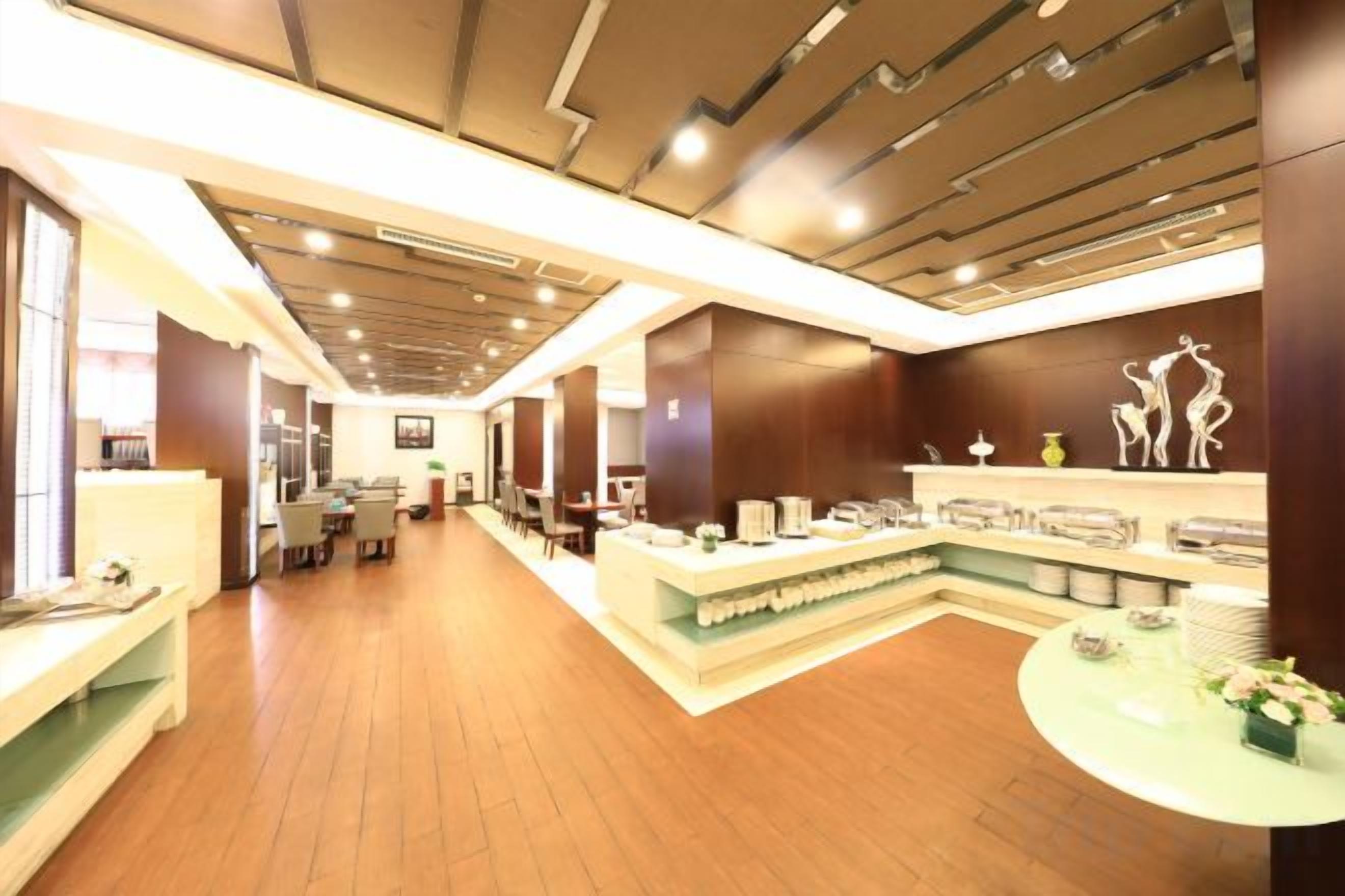 Un hall de hotel con mostrador de recepción, zona de estar y un largo pasillo.