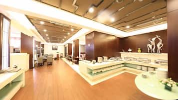 Un hall de hotel con mostrador de recepción, zona de estar y un largo pasillo.