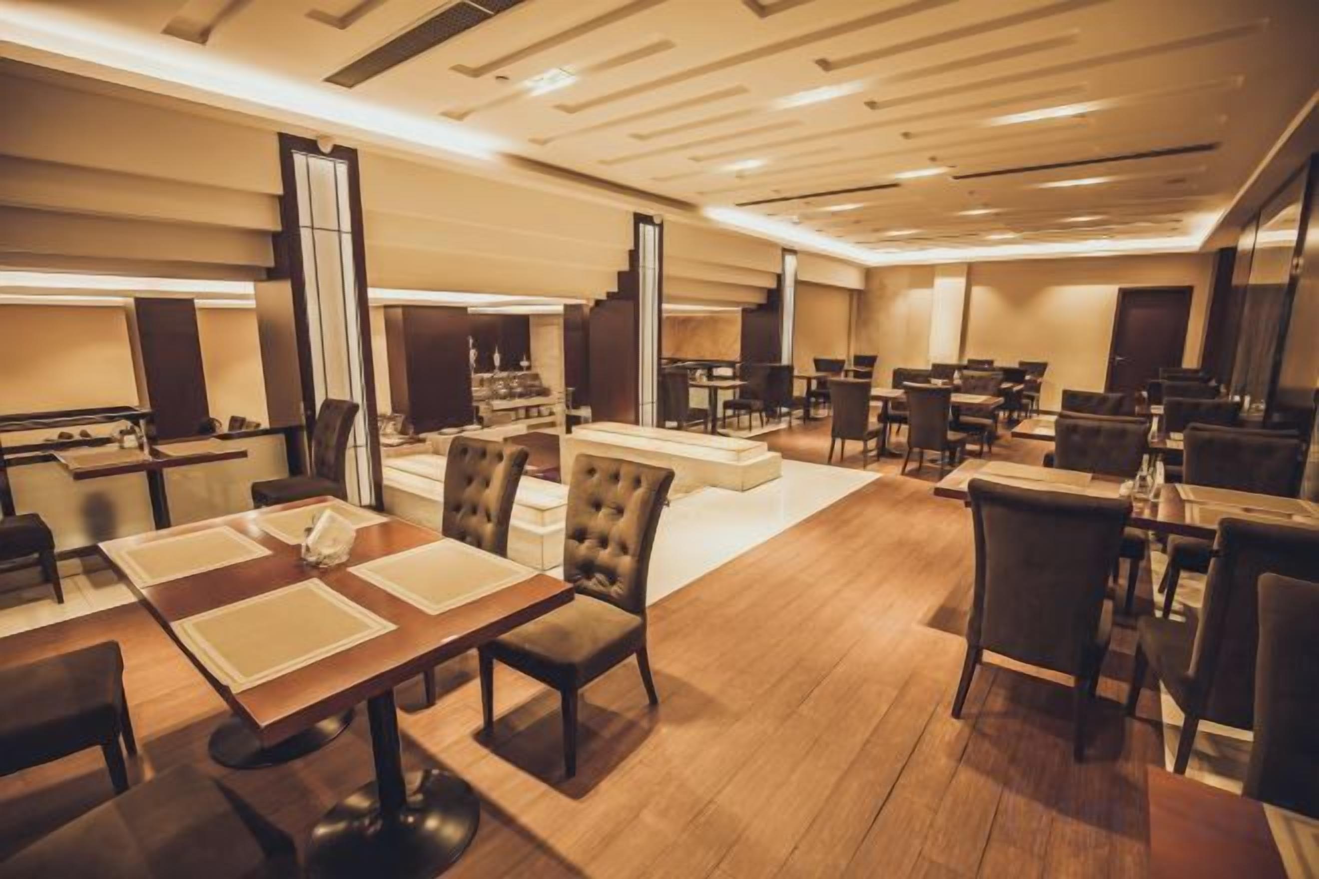A hotel lobby with multiple dining tables, chairs, and a central seating area.