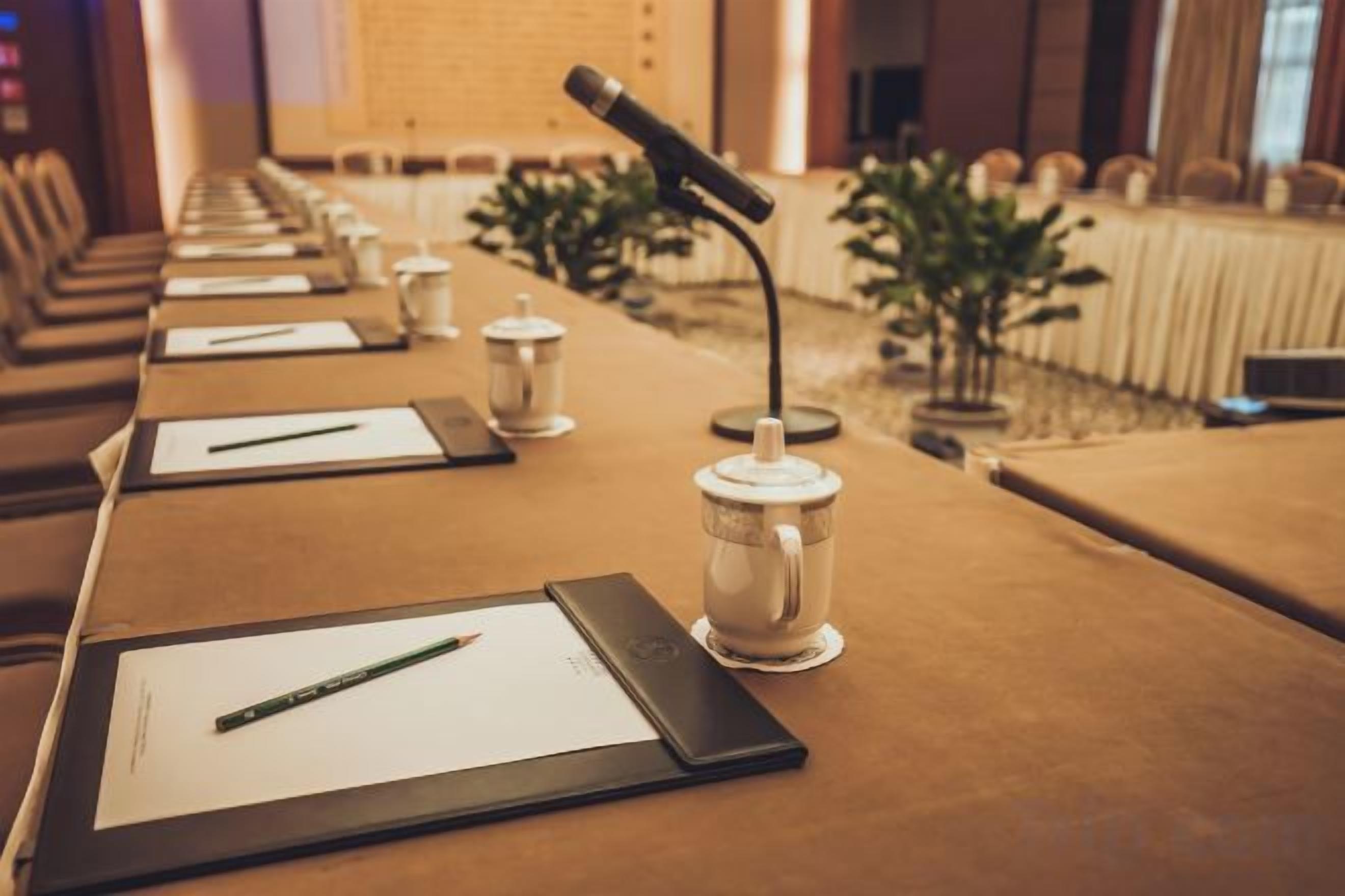 A conference room with a long table, microphones, and nameplates.