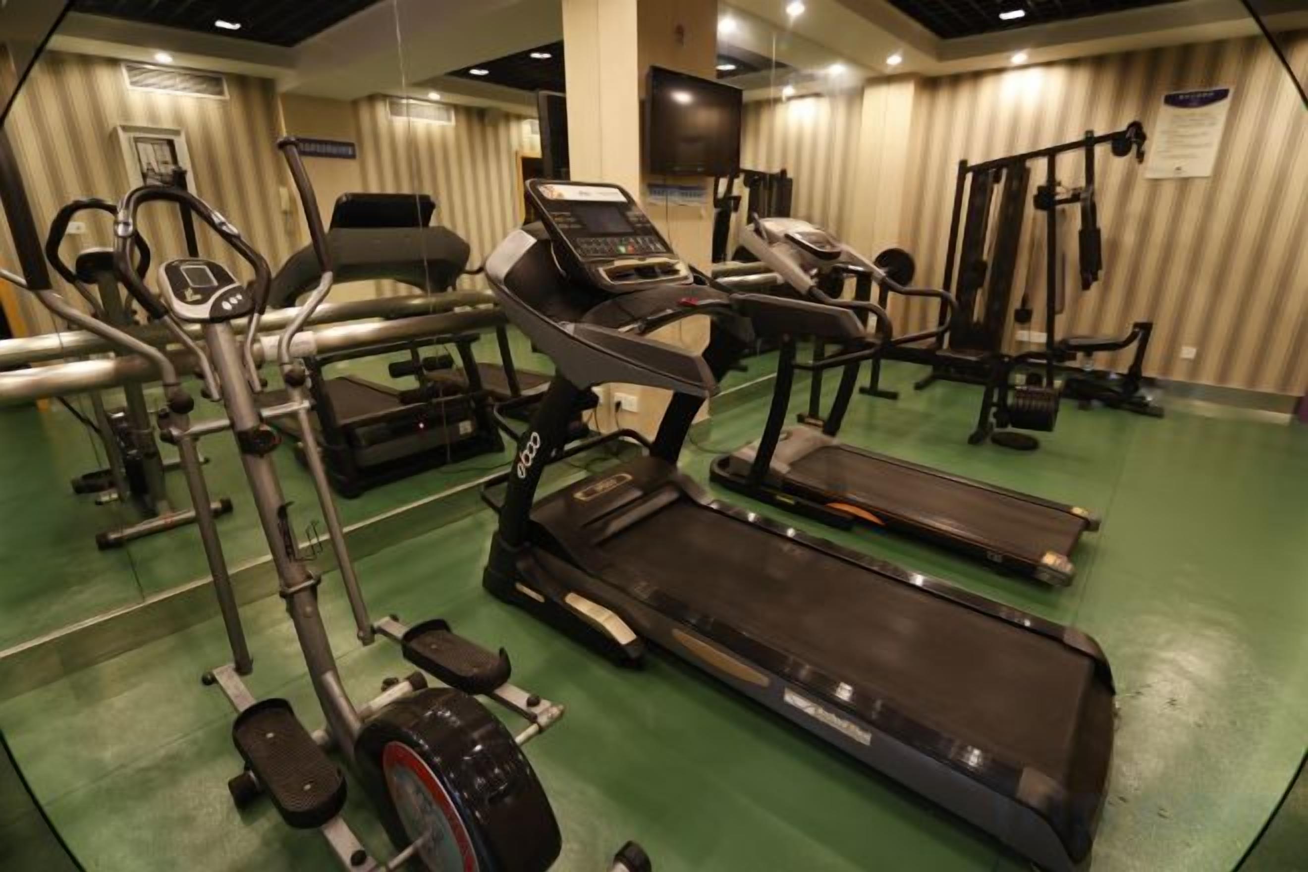 A gym with various exercise equipment including treadmills, stationary bikes, and weight machines.
