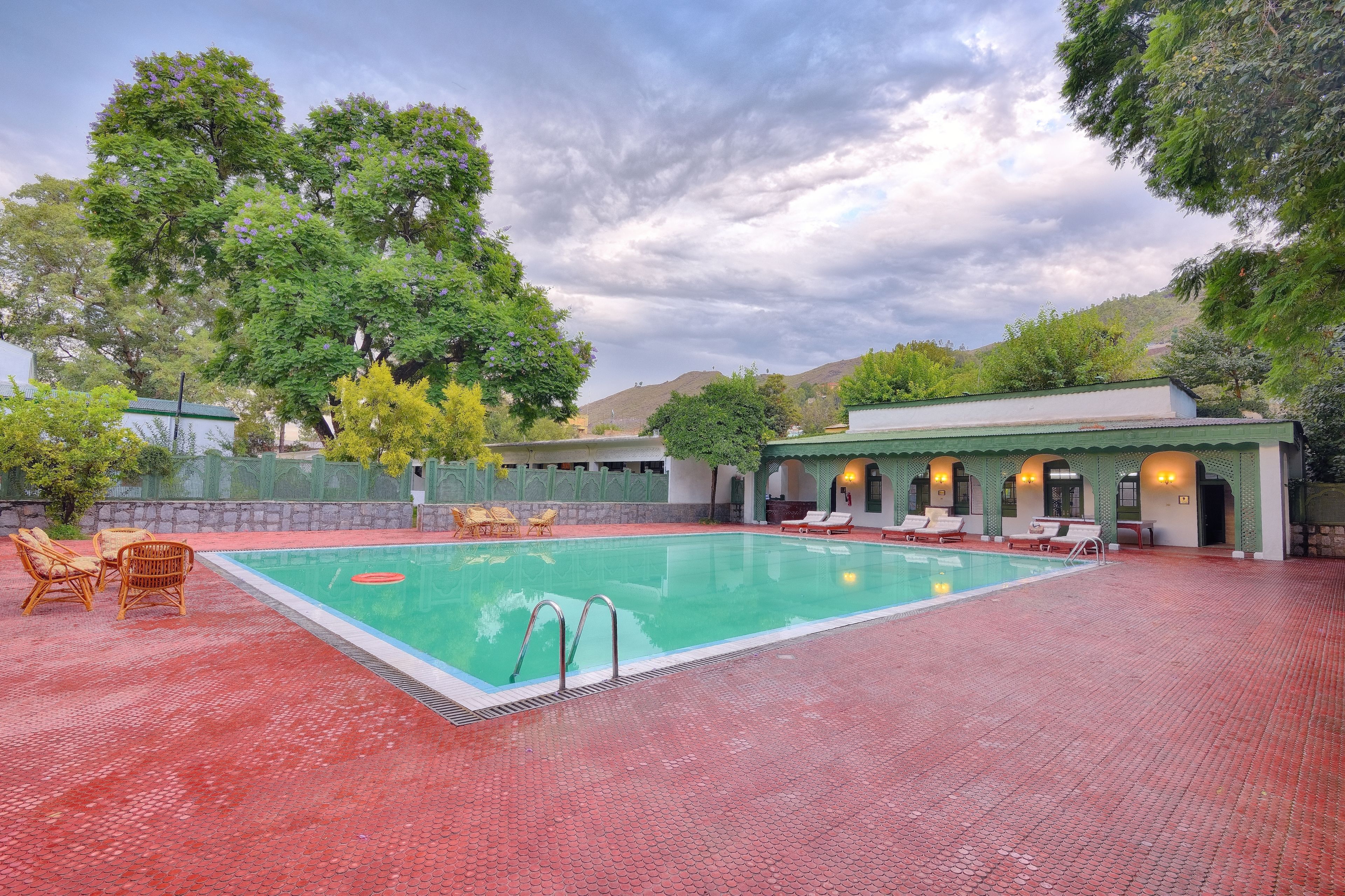 A swimming pool with lounge chairs and a covered seating area.
